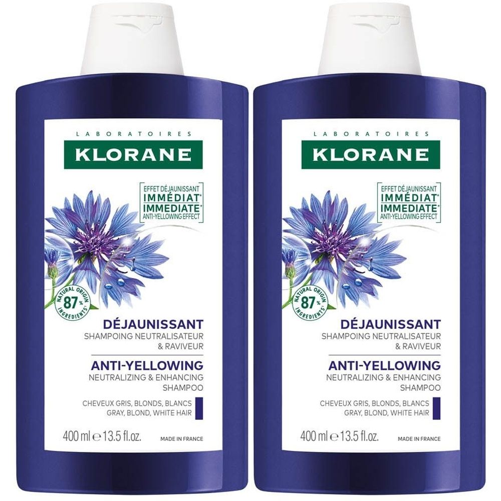 Twee blauwe shampoo flessen. Opschrift: Klorane, Déjaunissant, Anti-Yellowing Shampoo. Voor grijs, blond en wit haar.