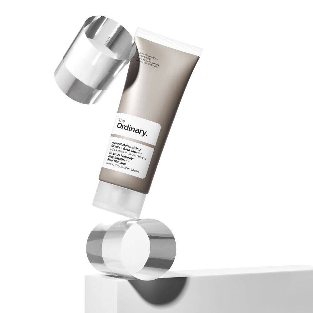 Tube in balans met twee transparante cilinders. Opschrift: The Ordinary, Natural Moisturizing Factors + Beta Glucan.