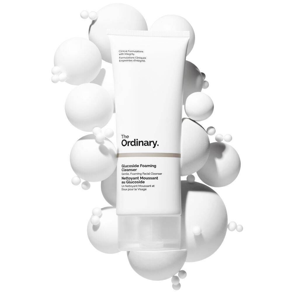 Een tube The Ordinary Glucoside Foaming Cleanser omgeven door witte bollen.