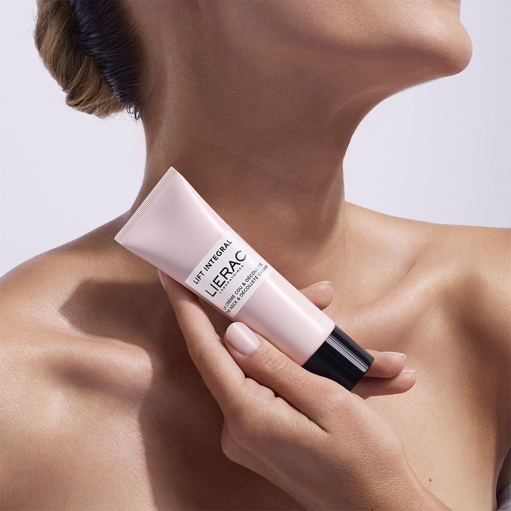 Persoon houdt een roze tube met zwarte dop vast. Opschrift: Lierac Lift Integral, La Crème Cou & Décolleté.