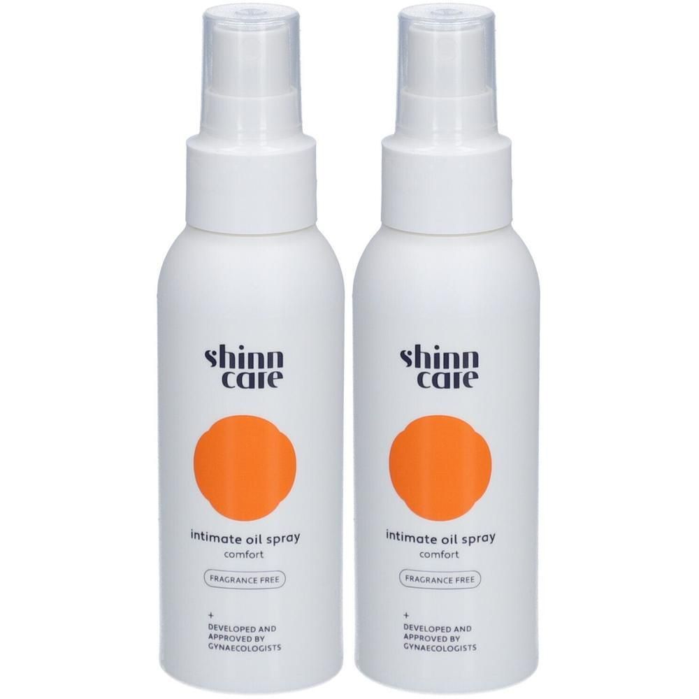 Twee witte spuitflessen met oranje cirkel. Opschrift: Shinn Care, Intimate Oil Spray, fragrance free.