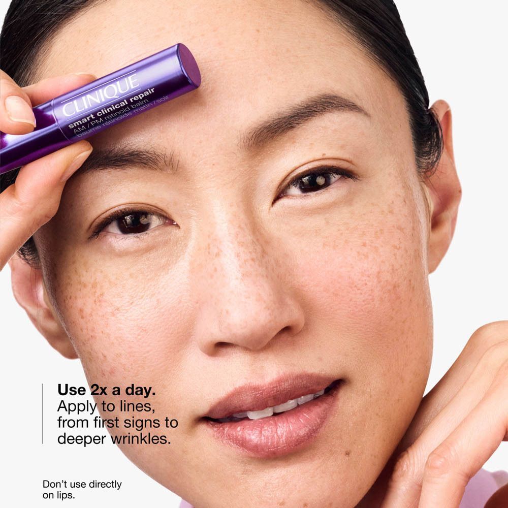 Une femme tient le baume Clinique Smart Clinical Repair AM/PM Retinoid sur son front.