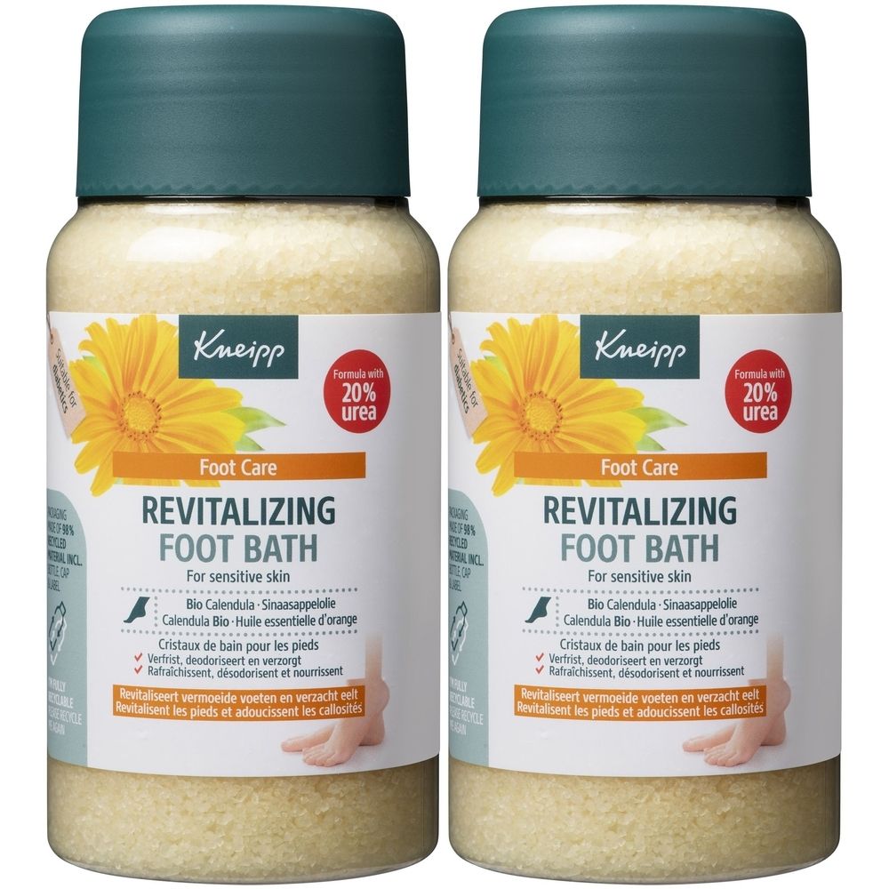 Twee flessen Kneipp voetbad. Beige vloeistof met groene dop. Etiket met bloem, tekst: Revitalizing Foot Bath, 20% ureum.