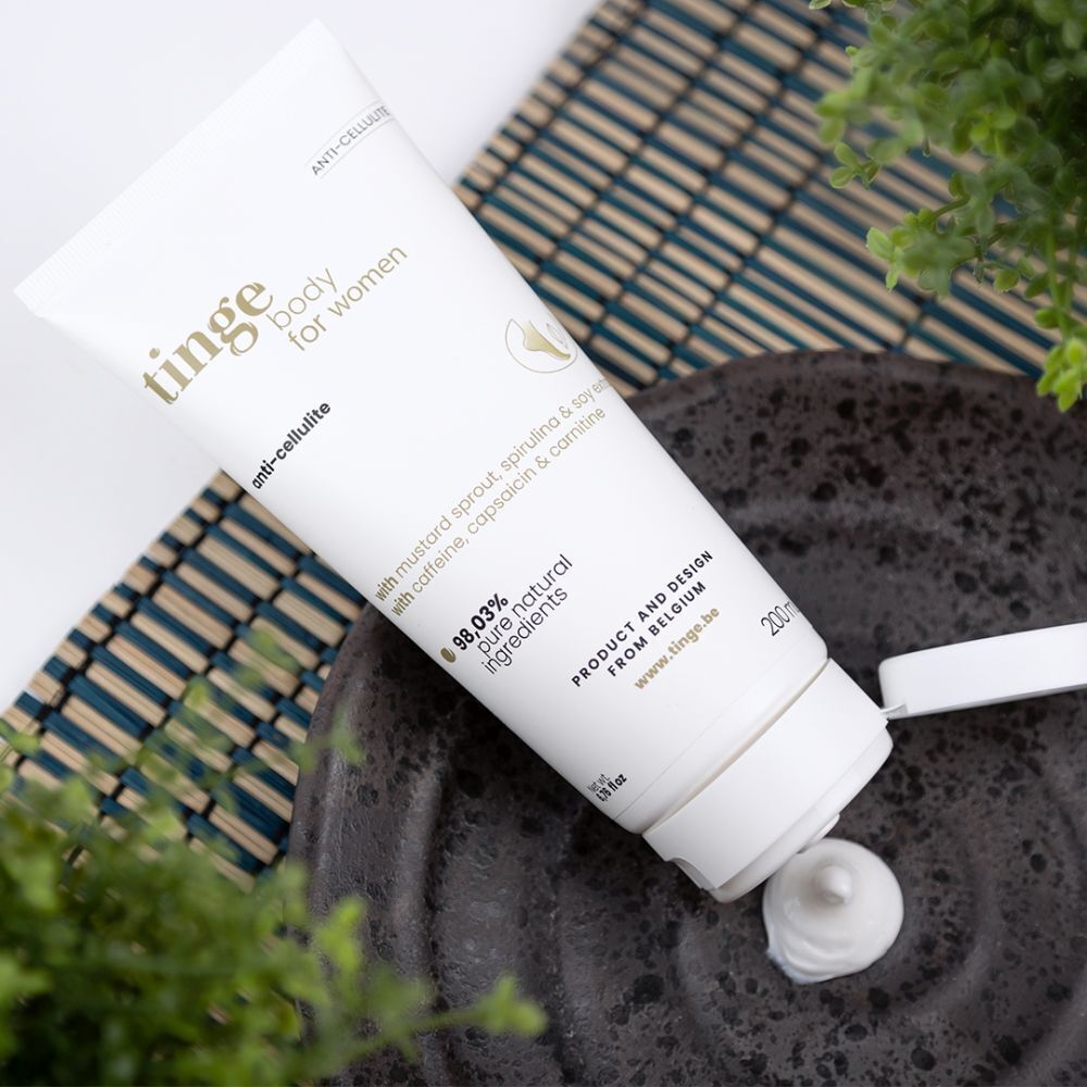 Crèmetube op ondergrond. Opschrift: Tinge body for women, anti-cellulite. Met ingrediënten. 98,03% pure natuurlijke ingrediënten. Product uit België.