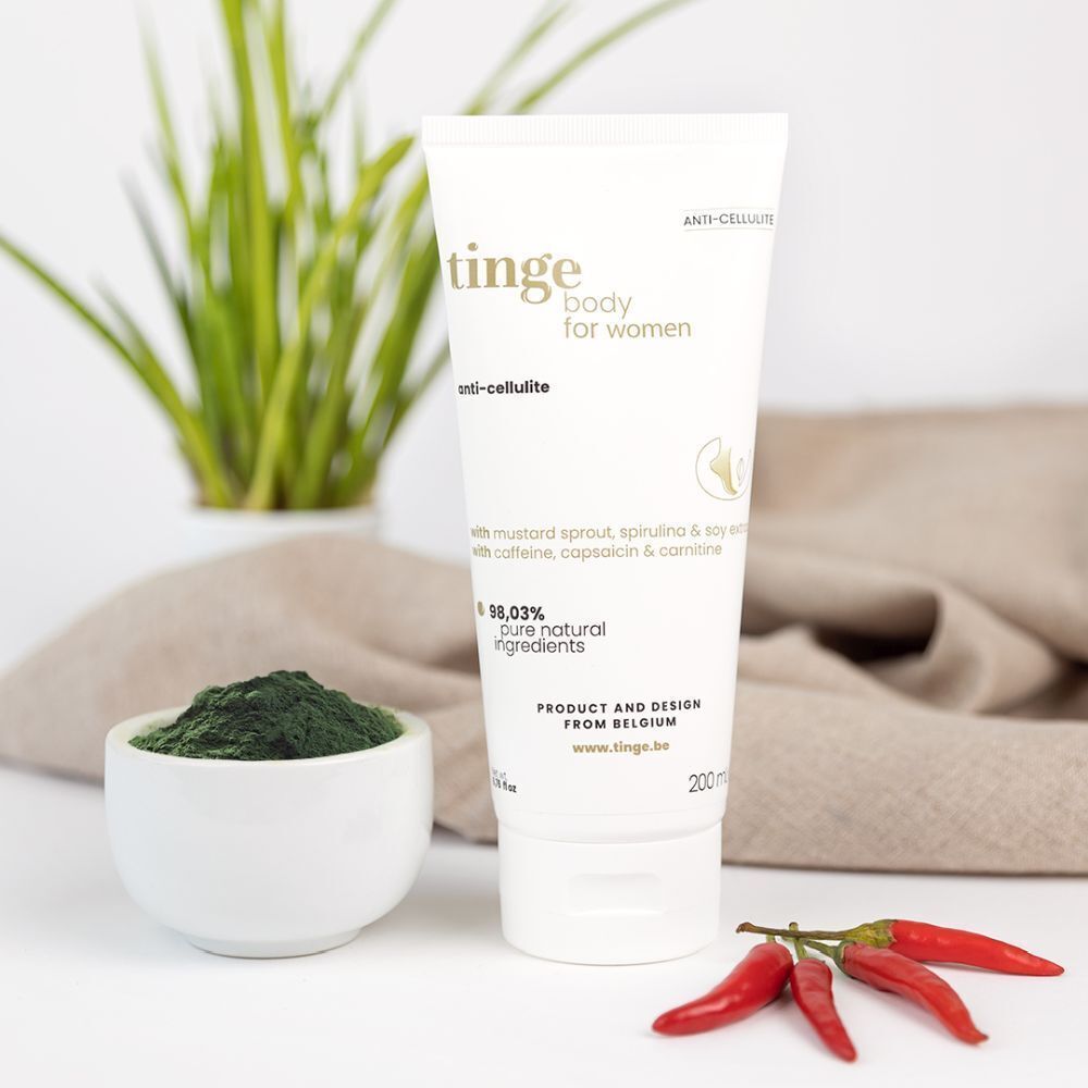 Crèmetube naast kom met poeder en pepers. Opschrift: Tinge body for women, anti-cellulite. Met ingrediënten. Product uit België.