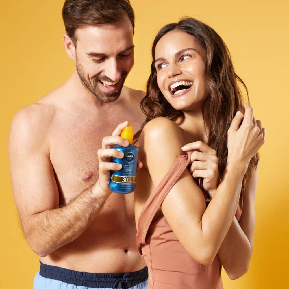 Man en vrouw met Nivea Sun Protect & Dry Touch Brume Solaire SPF30. Man houdt fles vast, vrouw lacht.