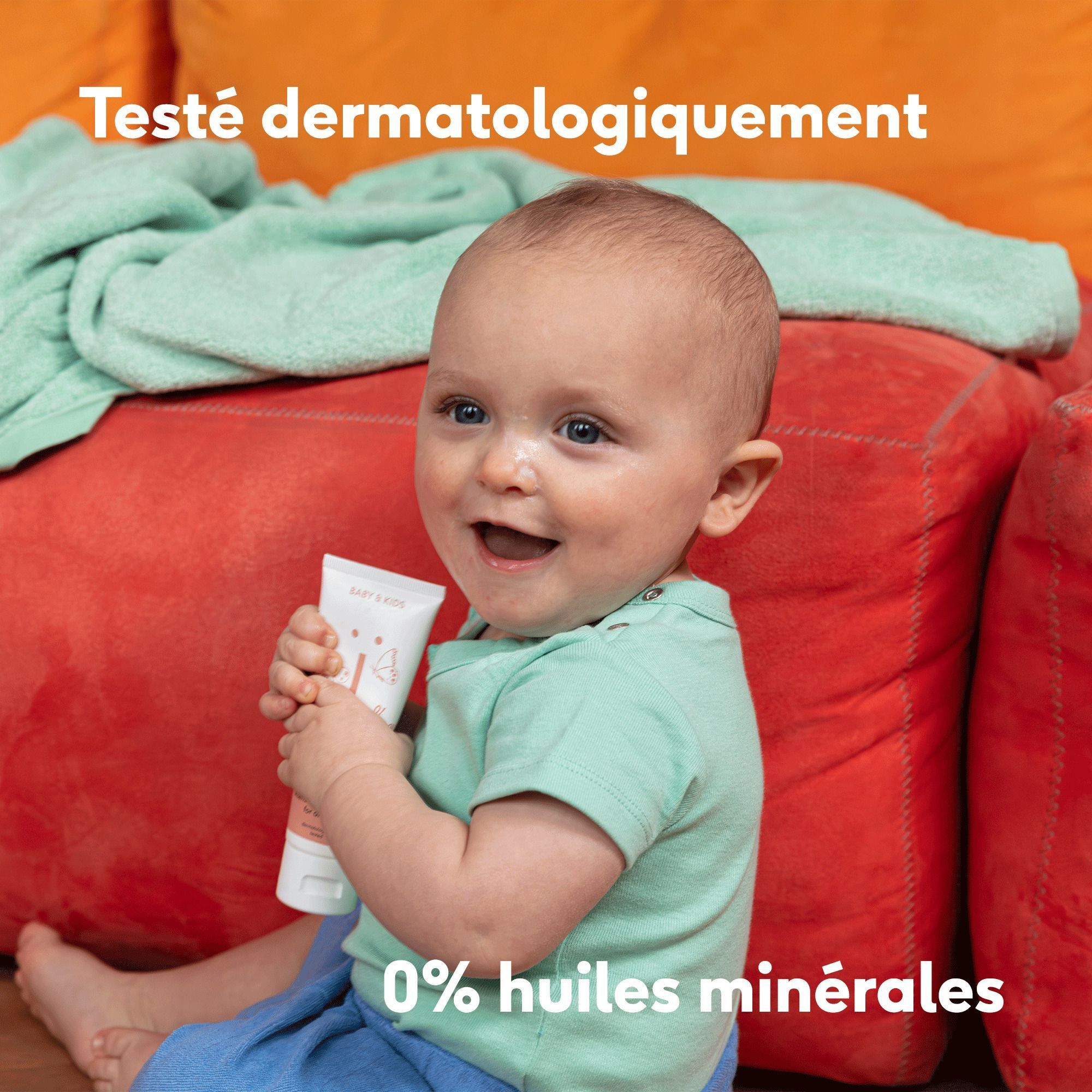Bébé tenant un tube de crème. "Testé dermatologiquement" et "0% huiles minérales" sont visibles.