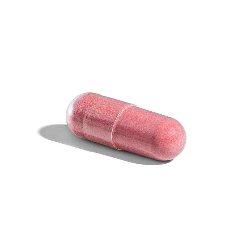 Een enkele roze capsule op een witte achtergrond. Capsule bestaat uit twee delen.