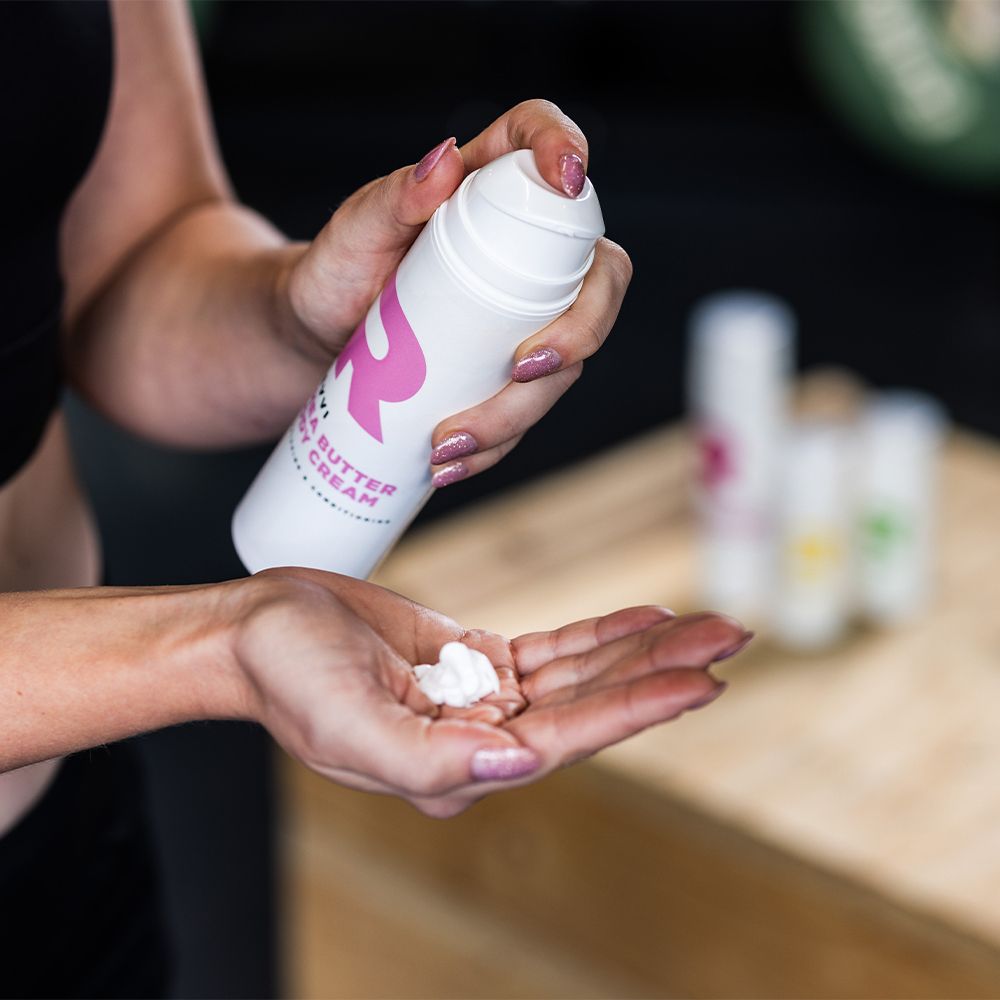 Mains tenant un flacon pompe blanc et de la crème. Autres flacons en arrière-plan.