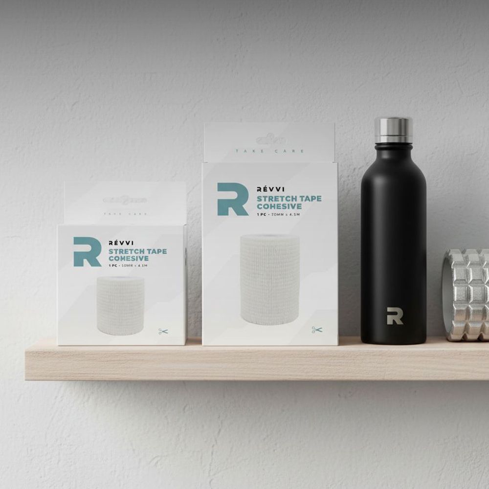 Twee verpakkingen met wit verband op een plank. RÉVVI, STRETCH TAPE COHESIVE. Daarnaast een drinkfles.