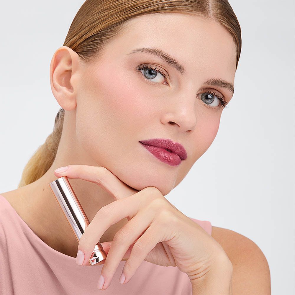 Vrouw met lipstick. Lipstick aangebracht op lippen. Roze top, lichte achtergrond.