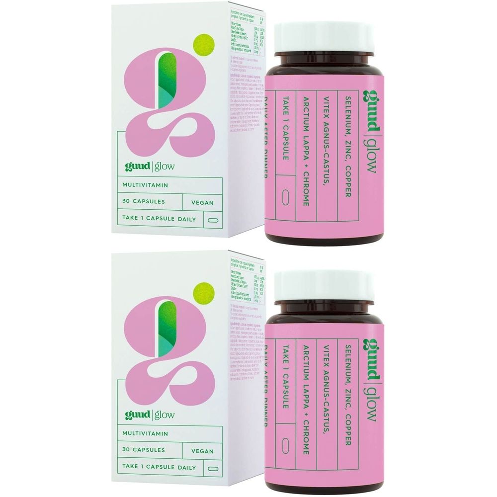 Twee roze flessen met witte etiketten en tekst. Opschrift: Guud Glow, ingrediënten. Daarnaast twee witte dozen.