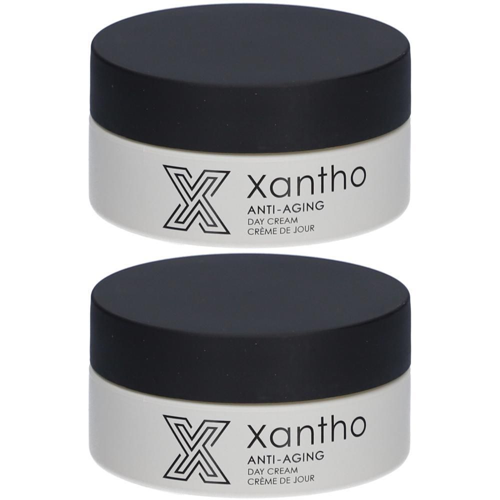 Deux pots de crème de jour anti-âge Xantho, couvercles noirs. Récipient blanc avec logo et texte.
