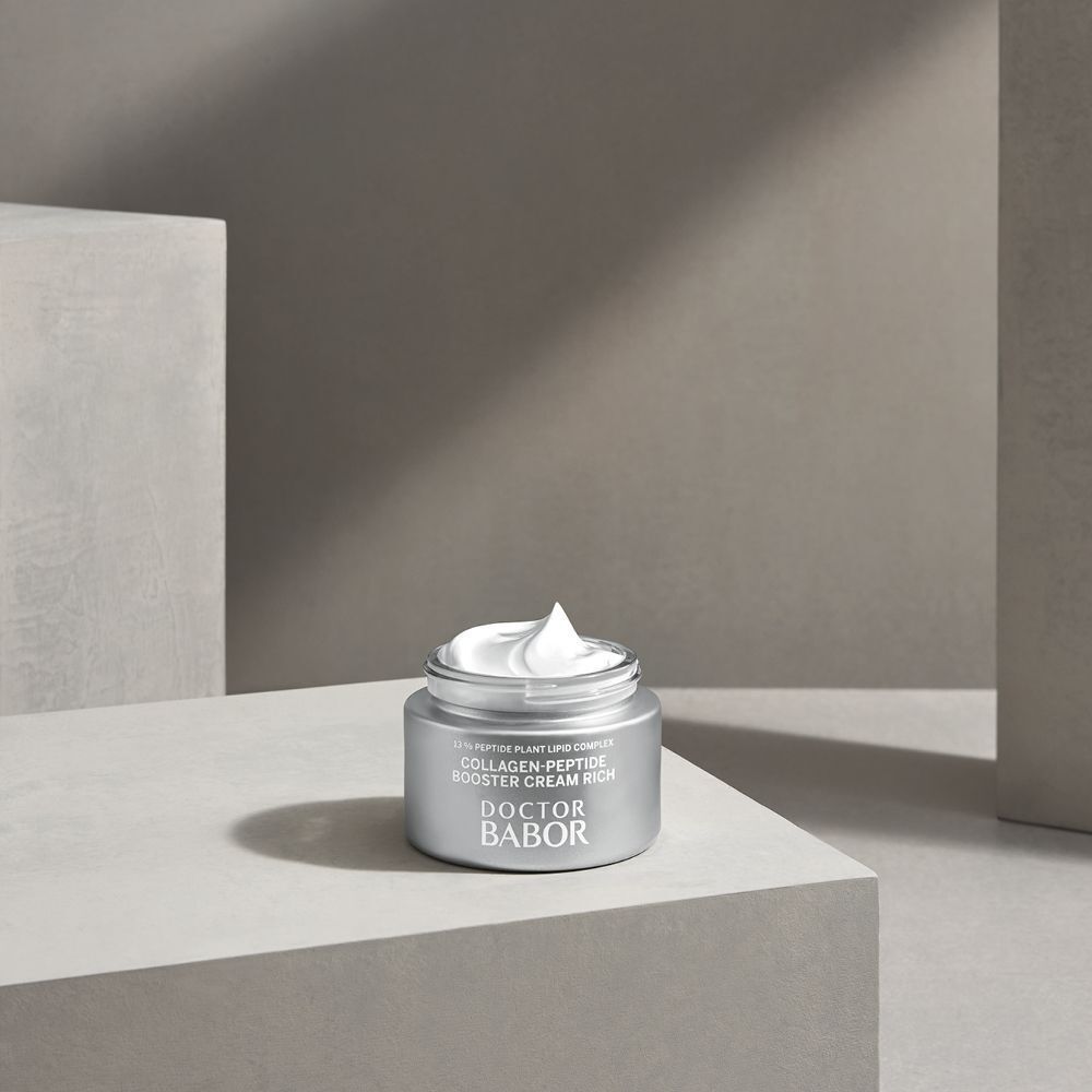 Pot argenté ouvert avec crème. Inscription: Collagen-Peptide Booster Cream Rich, Doctor Babor. Sur une surface.