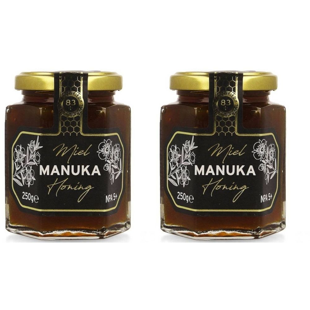 Deux pots de miel avec couvercles dorés. Étiquettes noires avec texte blanc: Miel Manuka Honing, NPA 5+. 250g.