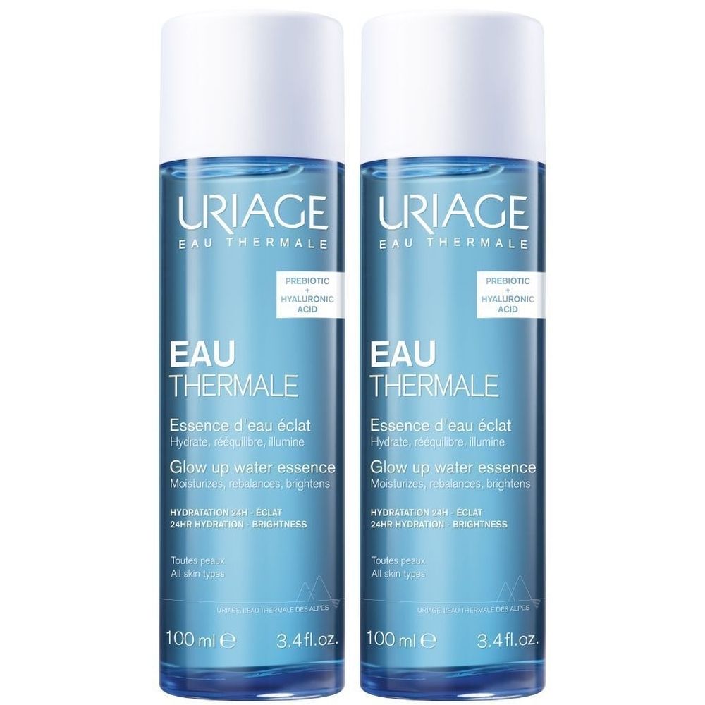 Twee flessen Uriage Eau Thermale Essence d'Eau Éclat. Blauwe flessen met witte dop. Tekst: Eau Thermale, Essence d'eau éclat, 100 ml.