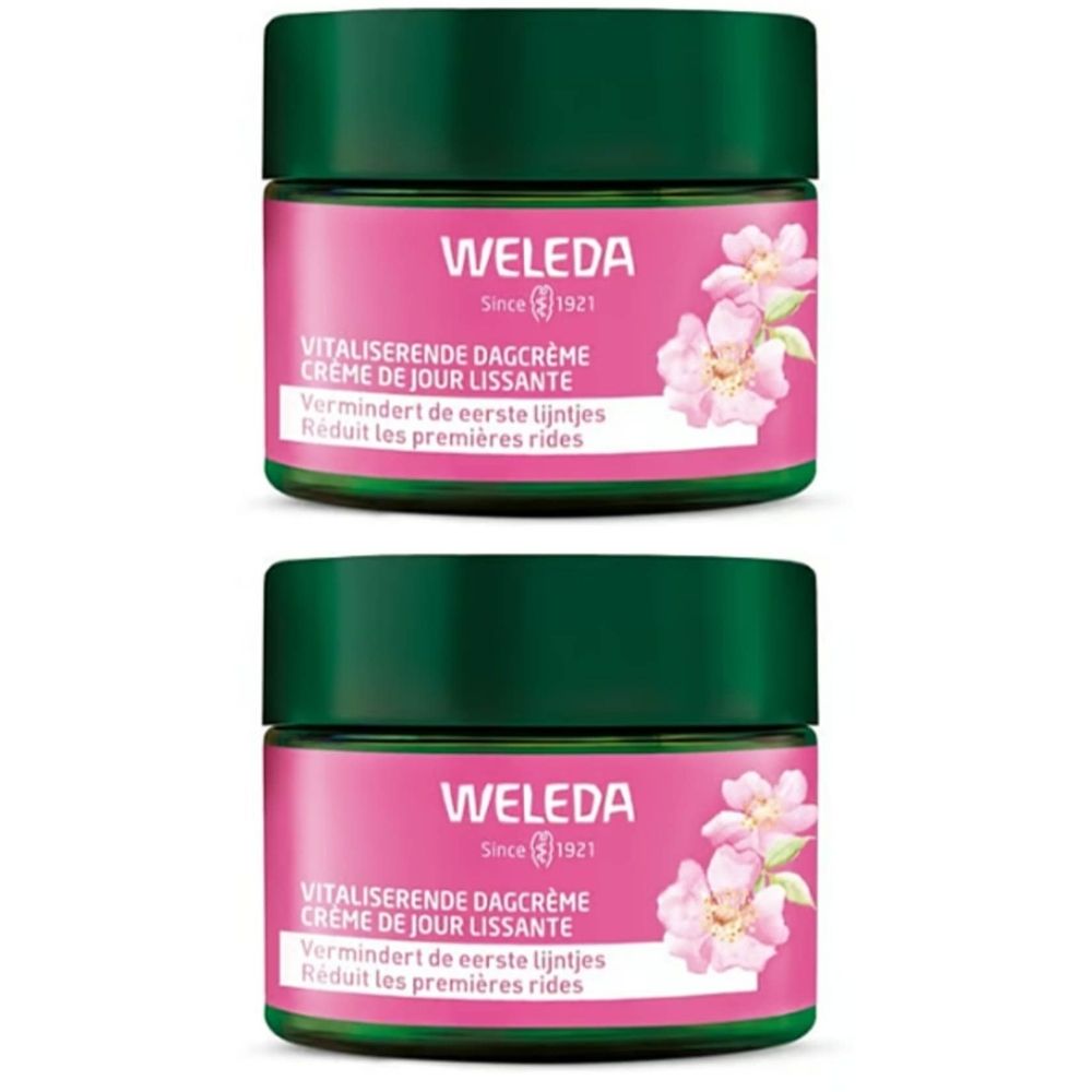 Twee crèmetiegels met groene deksels en roze etiketten. Opschrift: WELEDA, dagcrème, vermindert eerste lijntjes.
