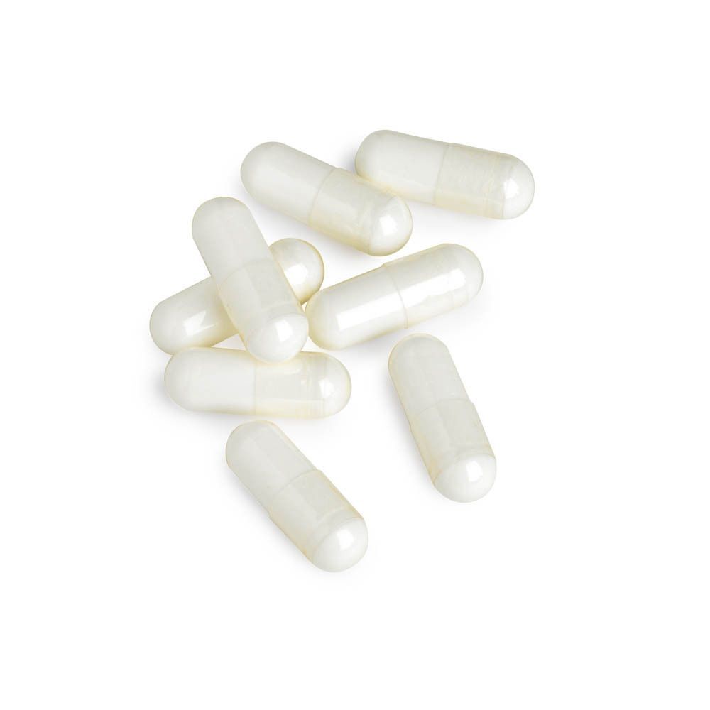 Plusieurs gélules blanches de L-Arginine sur fond blanc.