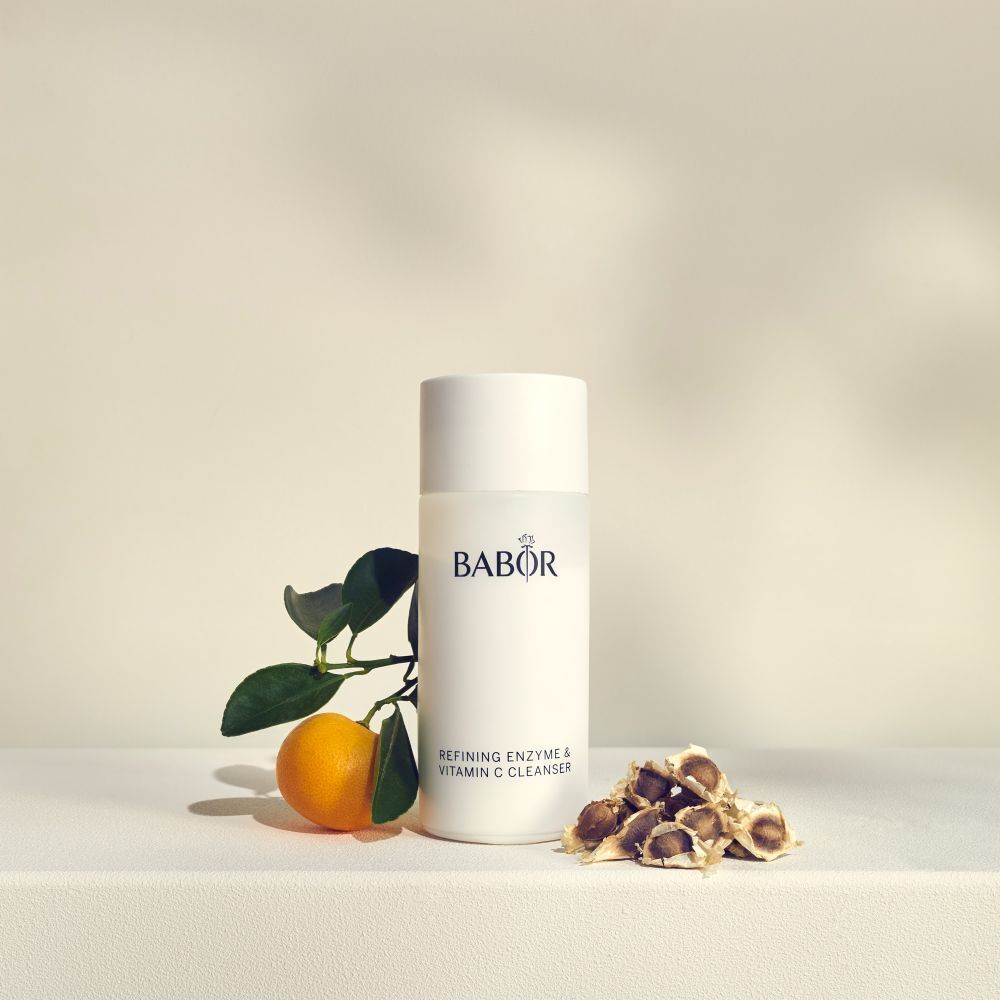 Flacon blanc avec logo BABOR et texte: Refining Enzyme & Vitamin C Cleanser. Avec orange et feuilles.