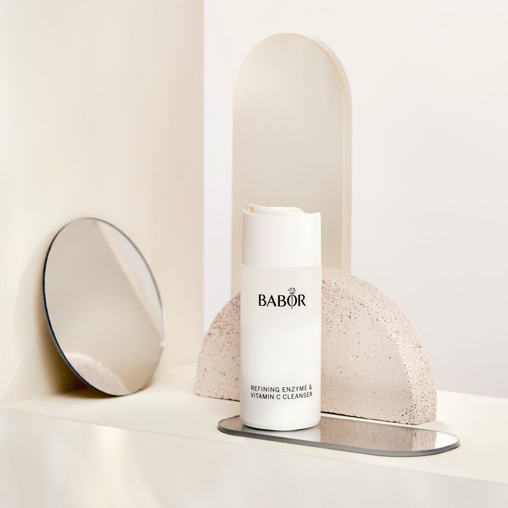 Flacon blanc avec logo BABOR et texte: Refining Enzyme & Vitamin C Cleanser. Sur une surface.