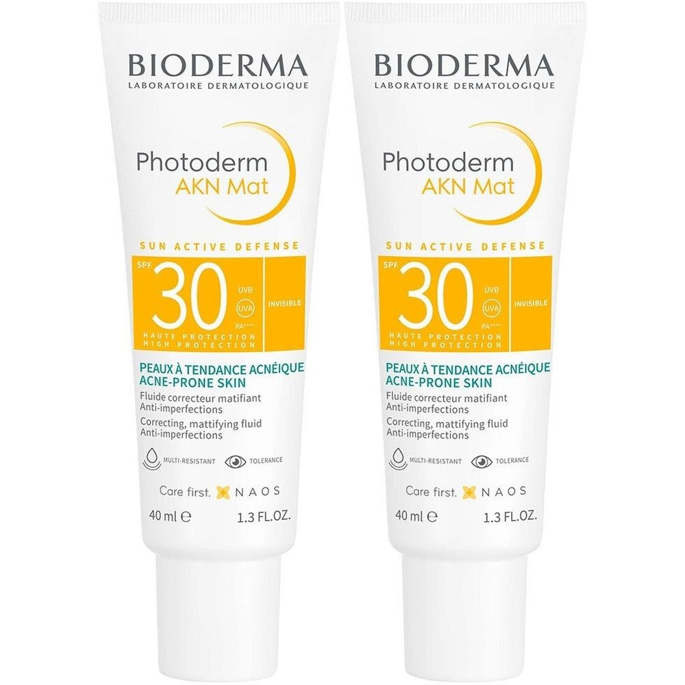 Twee tubes Bioderma Photoderm AKN Mat. Witte tubes met gele accenten. Tekst: Photoderm AKN Mat, SPF 30, voor acnegevoelige huid.