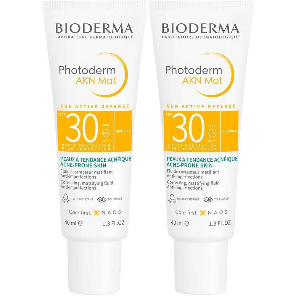 Twee tubes BIODERMA Photoderm AKN Mat SPF30. Witte tubes met gele accenten. Tekst: SPF 30, Peaux à tendance acnéique.