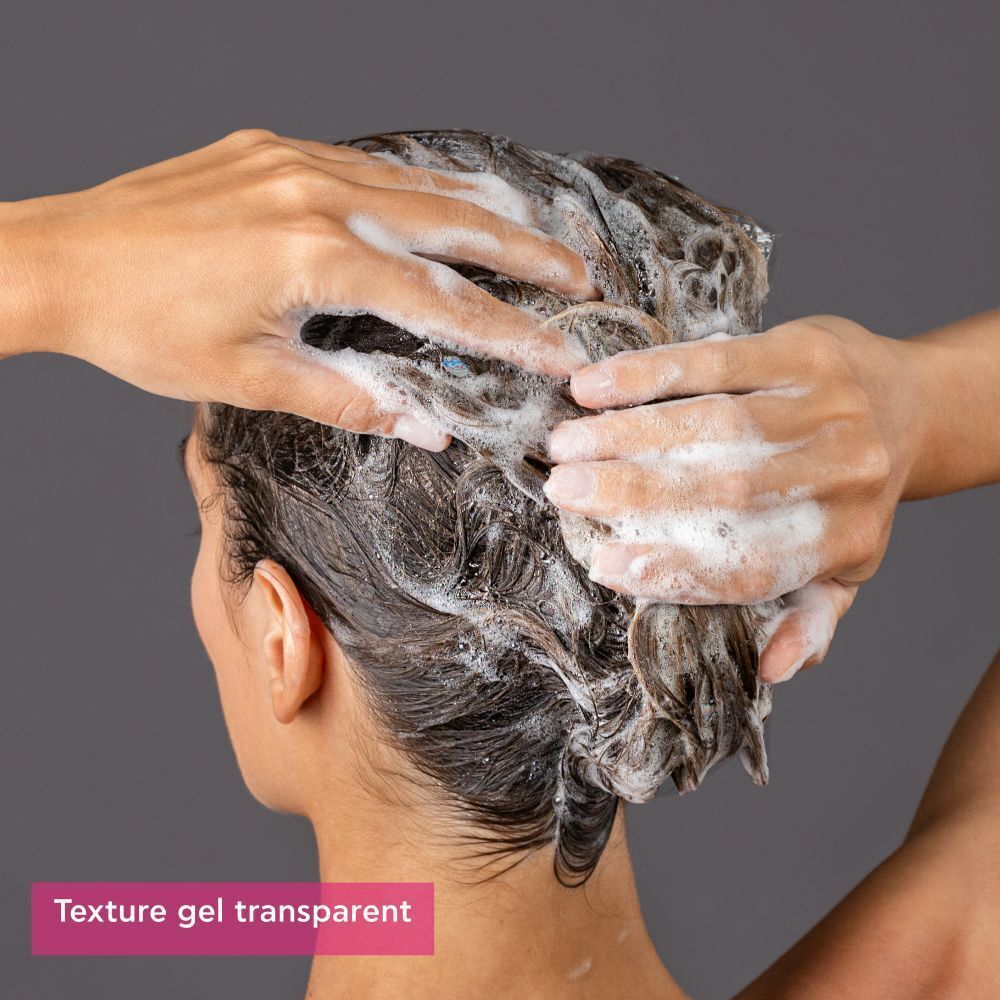 Mains lavant les cheveux avec le shampooing Apivita Tonic pour femmes. Mousse.
