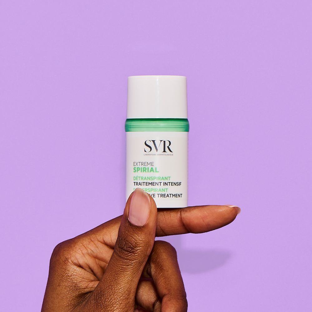 Witte deodorant, vastgehouden door een hand. Opschrift: SVR, Spirial Extreme, antitranspirant, intensieve behandeling. Paarse achtergrond.