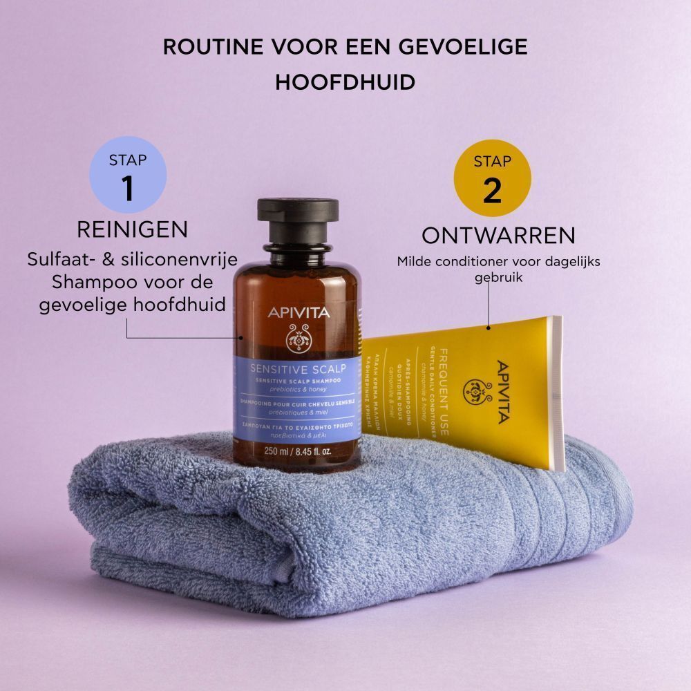 Shampoo, conditioner en handdoek. Tekst: Apivita Sensitive Scalp Shampoo. Stap 1: Reinigen.