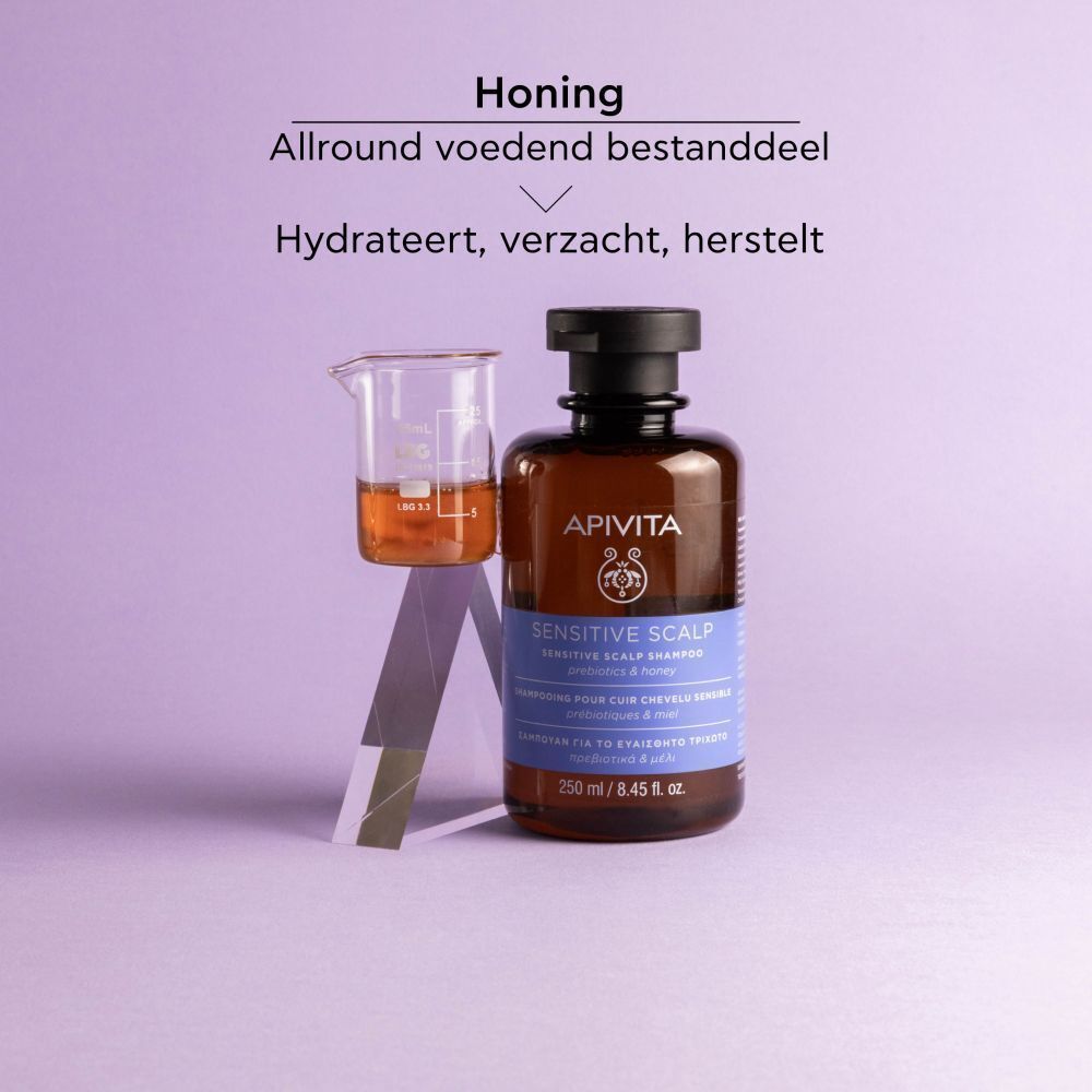 Shampoo fles en bekerglas met vloeistof. Tekst: Apivita Sensitive Scalp Shampoo. Honing.
