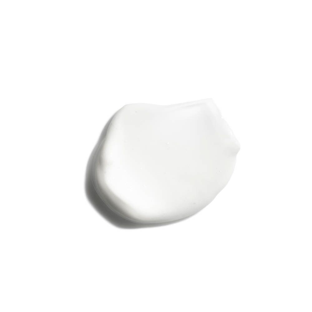 Une goutte de lotion blanche sur fond blanc. Aucune inscription visible.