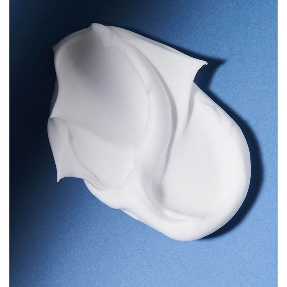 Close-up van witte scheerschuim op blauwe achtergrond. De crème heeft een golvende vorm.