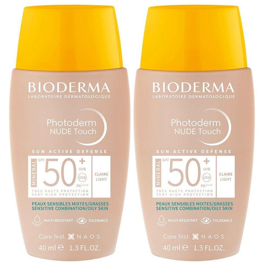 Deux flacons Bioderma Photoderm Nude Touch SPF50+. Flacons beiges avec bouchon jaune. Texte: SPF 50, Nude Touch, peaux mixtes.