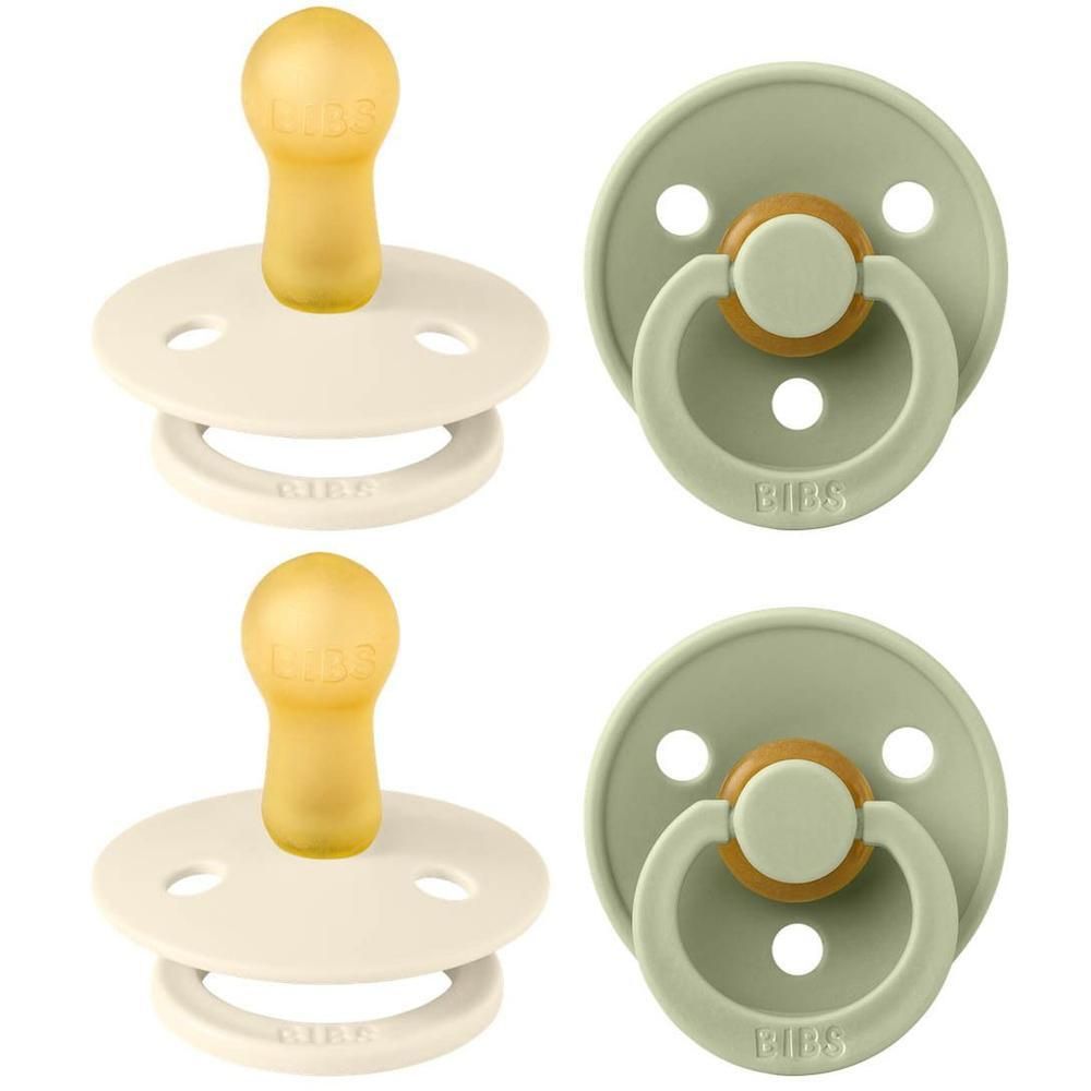 Twee spenen, ivoor en groen, met ronde schilden en kersvormige spenen. Ringen met BIBS-opschrift.