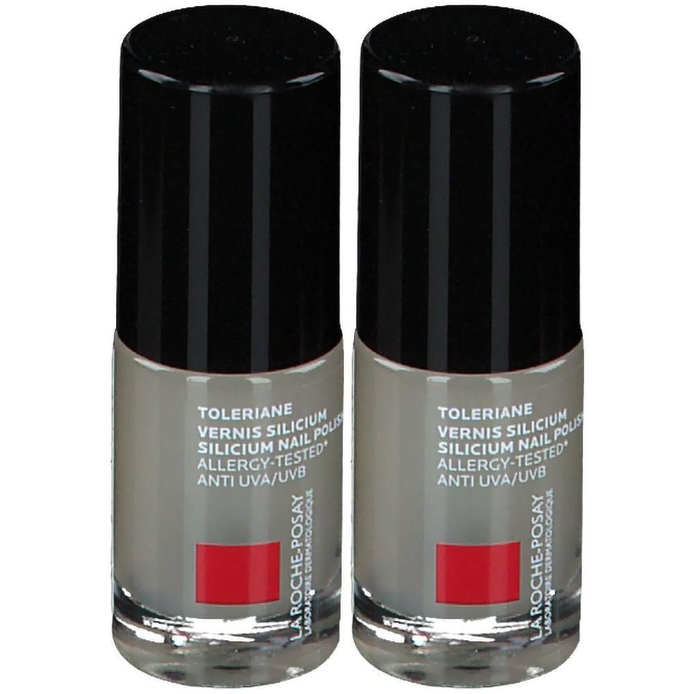 Twee flesjes grijze nagellak met zwarte doppen. Opschriften: Toleriane, Silicium Nail Polish, La Roche-Posay. Rood blok.