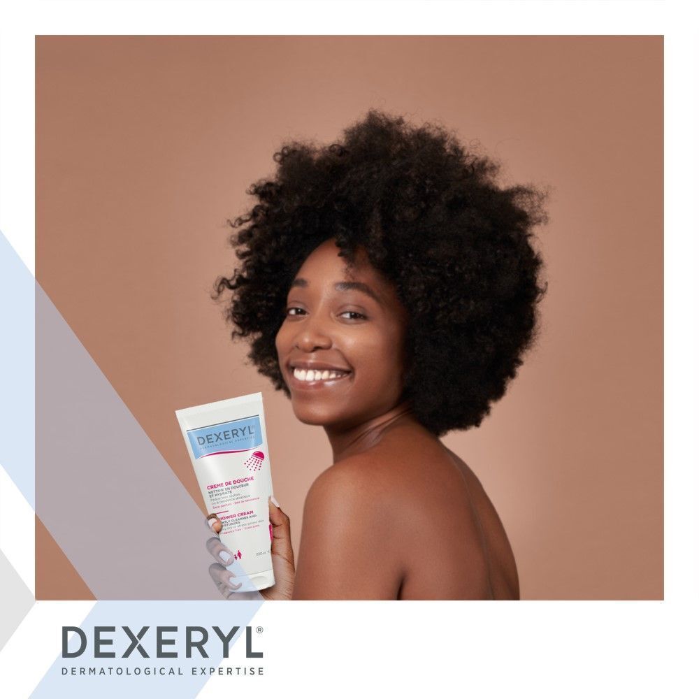 Femme tenant un tube de Dexeryl Crème De Douche. Blanc, avec texte bleu et rose.