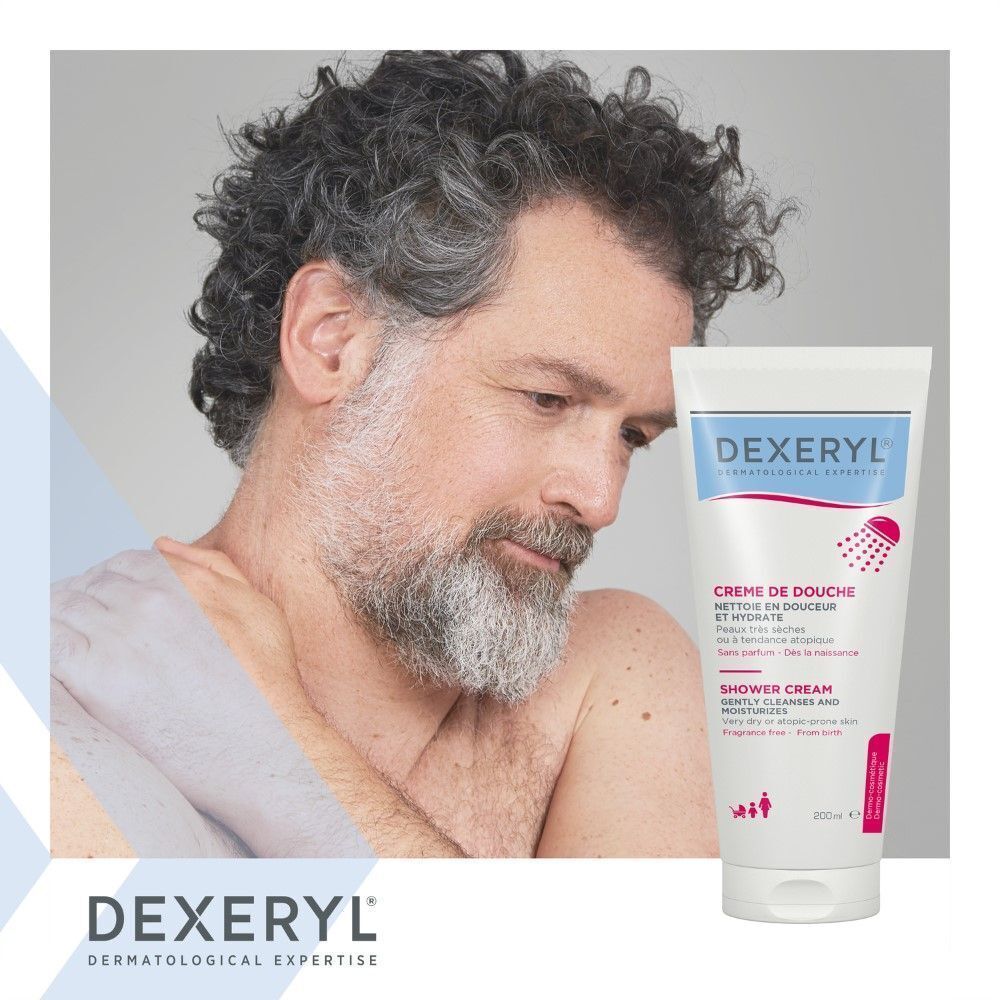 Homme barbu tenant un tube de Dexeryl Crème De Douche. Blanc, avec texte bleu et rose.