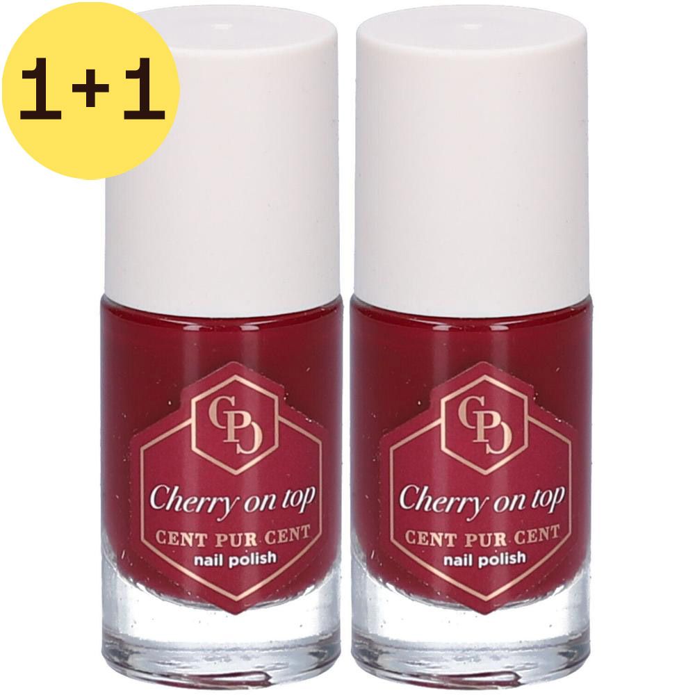 Deux flacons de vernis à ongles rouge cerise. Inscription : Cherry on top, CENT PUR CENT nail polish. Bouchons blancs, flacons en verre clair.