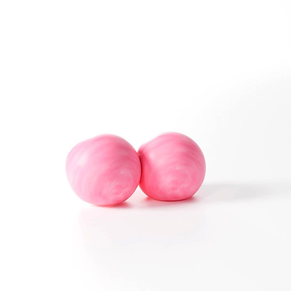 Twee roze oordopjes van was. Ronde vorm, licht onregelmatig oppervlak. Op witte achtergrond.