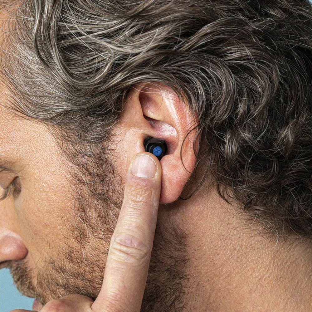 Homme insérant un bouchon d'oreille dans son oreille. Bouchon noir avec filtre bleu dans l'oreille.