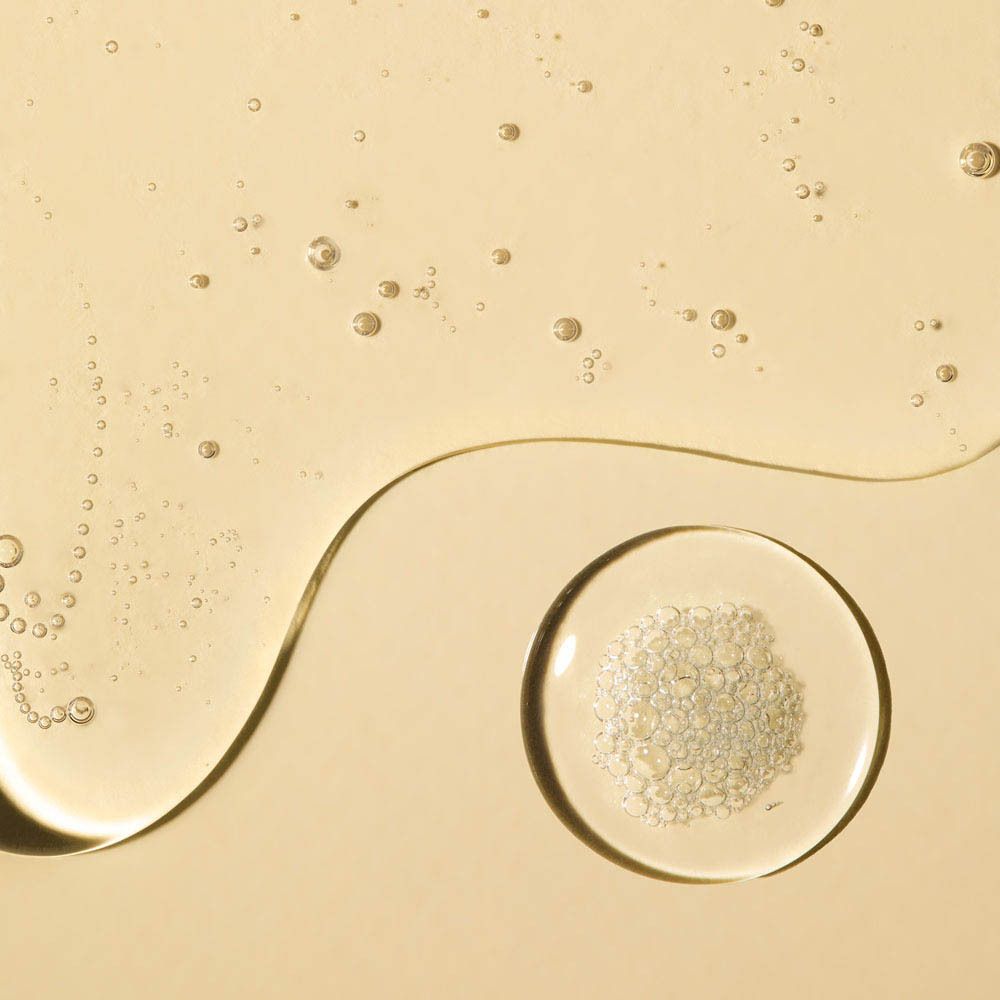 Gros plan sur du liquide et un petit bol avec des particules blanches. Fond jaune.