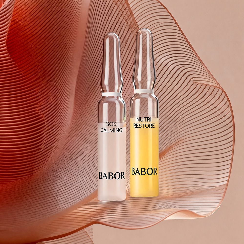 Twee Babor ampullen, SOS Calming en Nutri Restore, tegen een bloemenachtergrond.