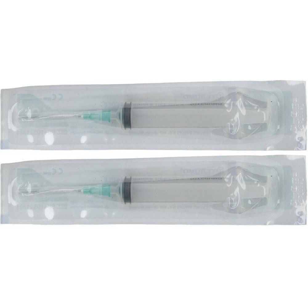 Deux seringues emballées avec aiguilles. Cylindres transparents, pistons noirs, bases d'aiguilles vertes. Dans des emballages transparents.