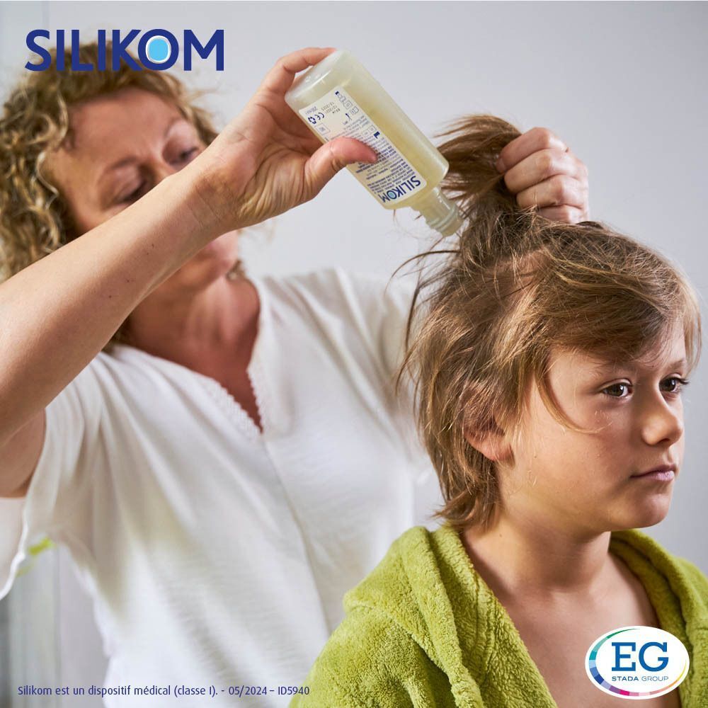 Femme versant du shampooing sur la tête d'un garçon. Garçon avec une serviette verte. Arrière-plan de salle de bain.