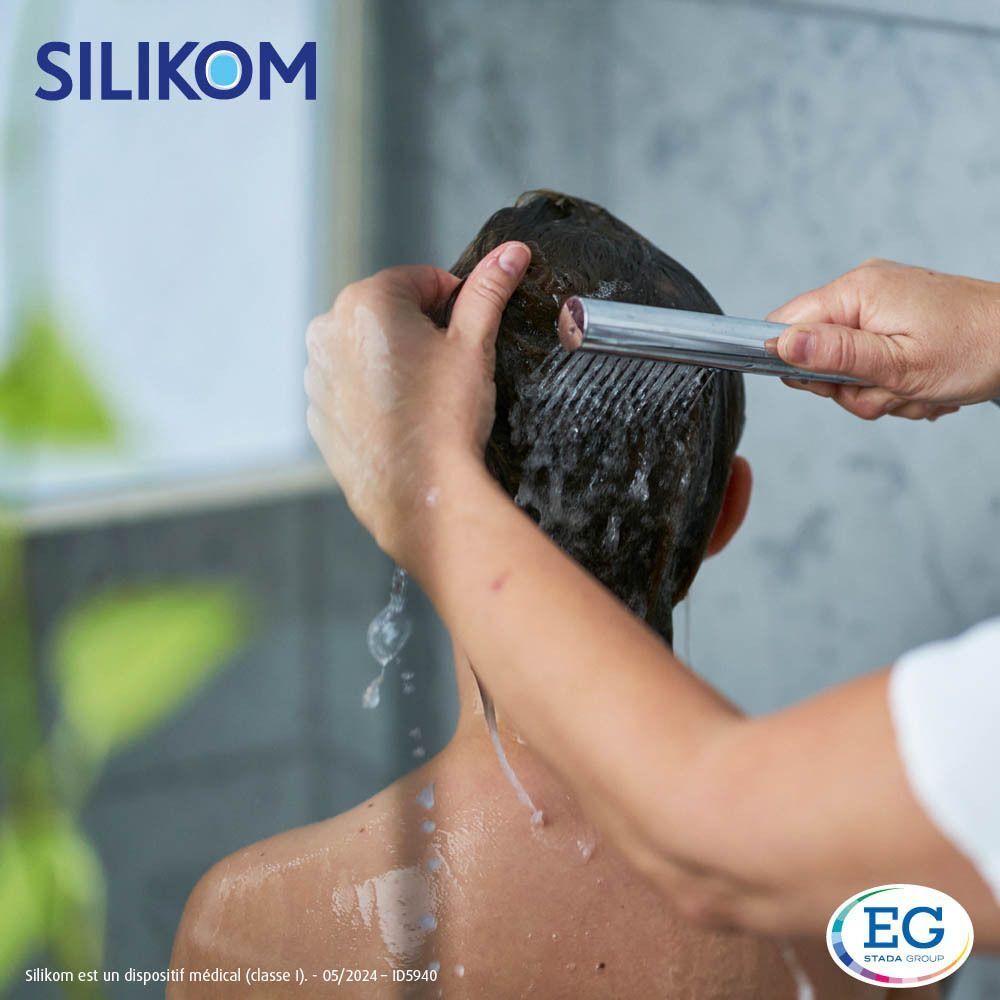Garçon sous la douche, cheveux rincés. Seul le logo Silikom est visible.