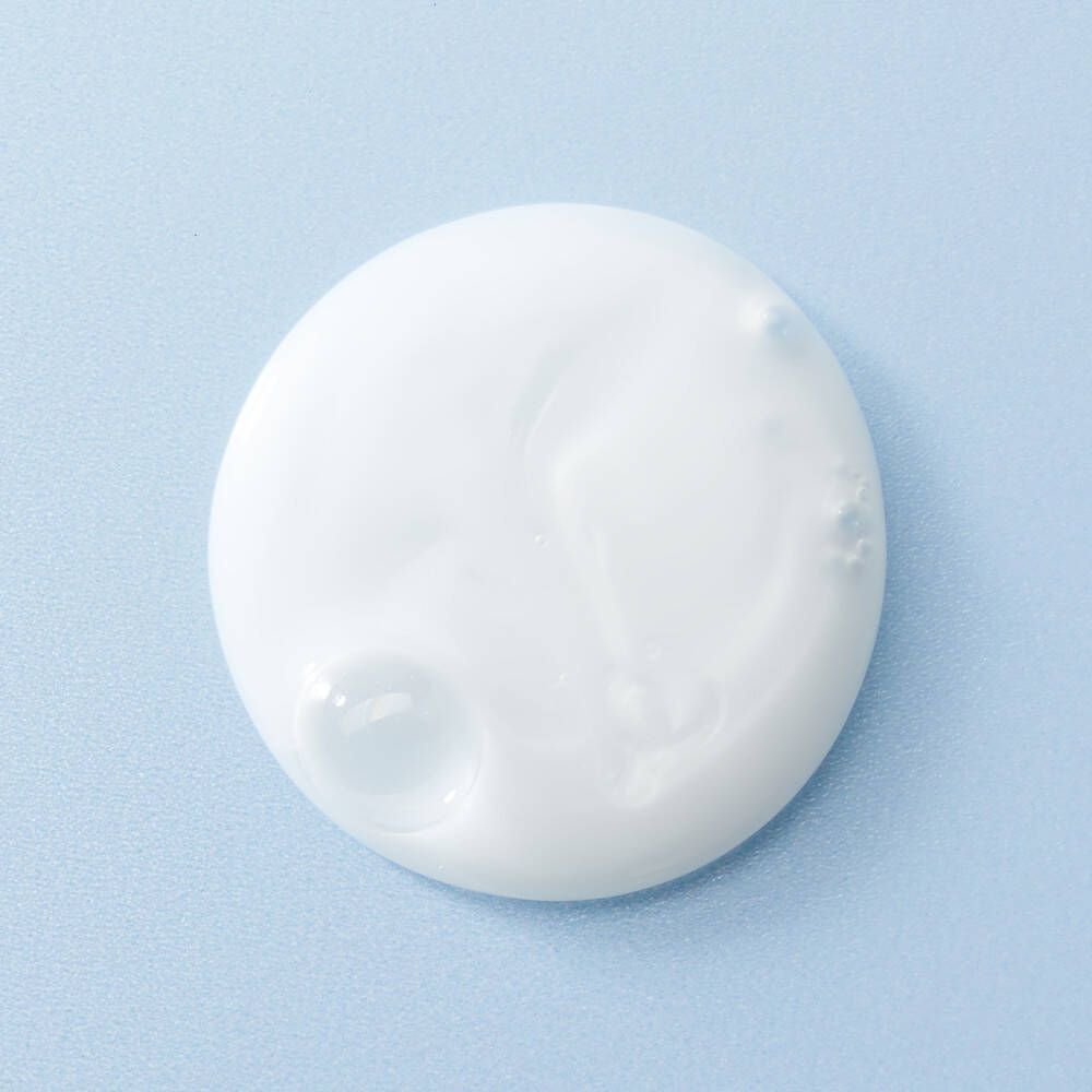 Witte klodder crème op lichtblauwe achtergrond. Ronde vorm met een kleinere bel.