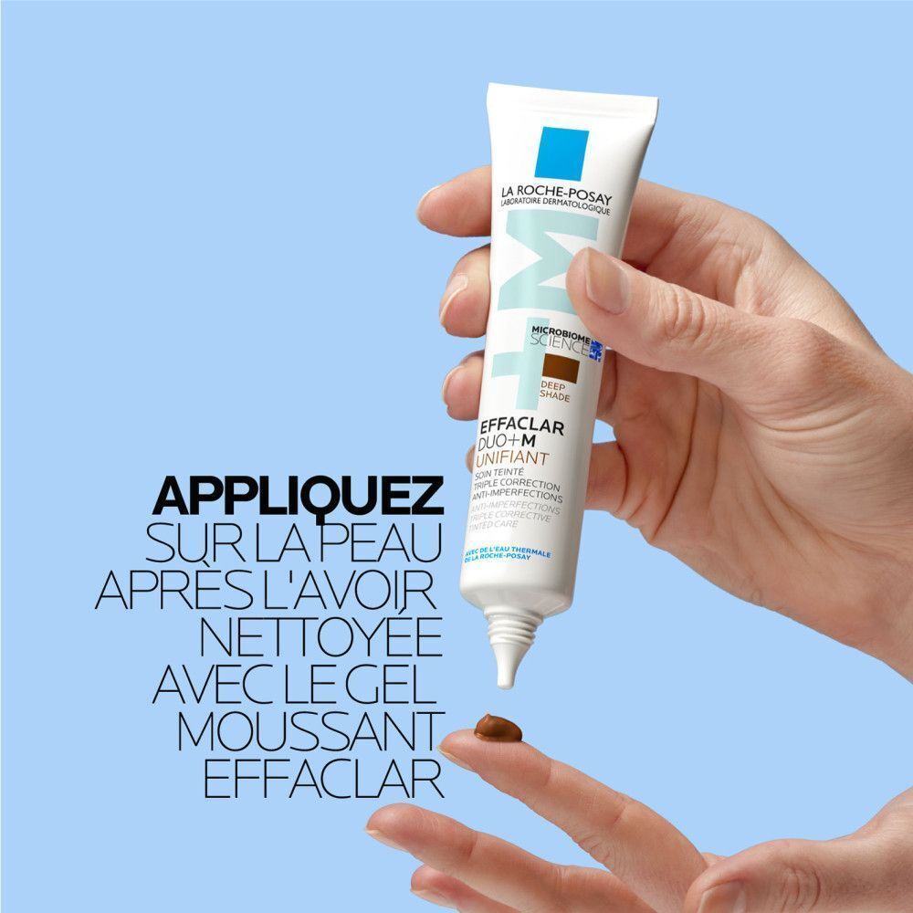 Main appliquant la crème La Roche-Posay Effaclar Duo+M sur le doigt. Goutte de crème visible.
