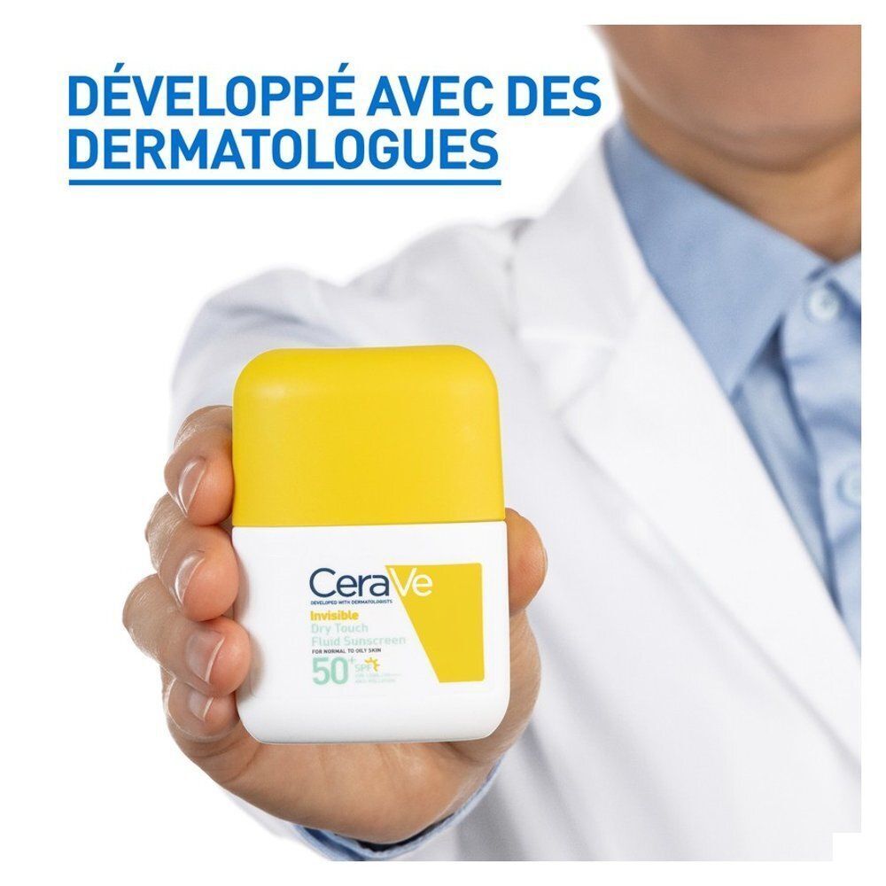 Main tenant un flacon blanc à bouchon jaune. Inscription : CeraVe, Invisible Dry Touch Fluid Sunscreen SPF50.