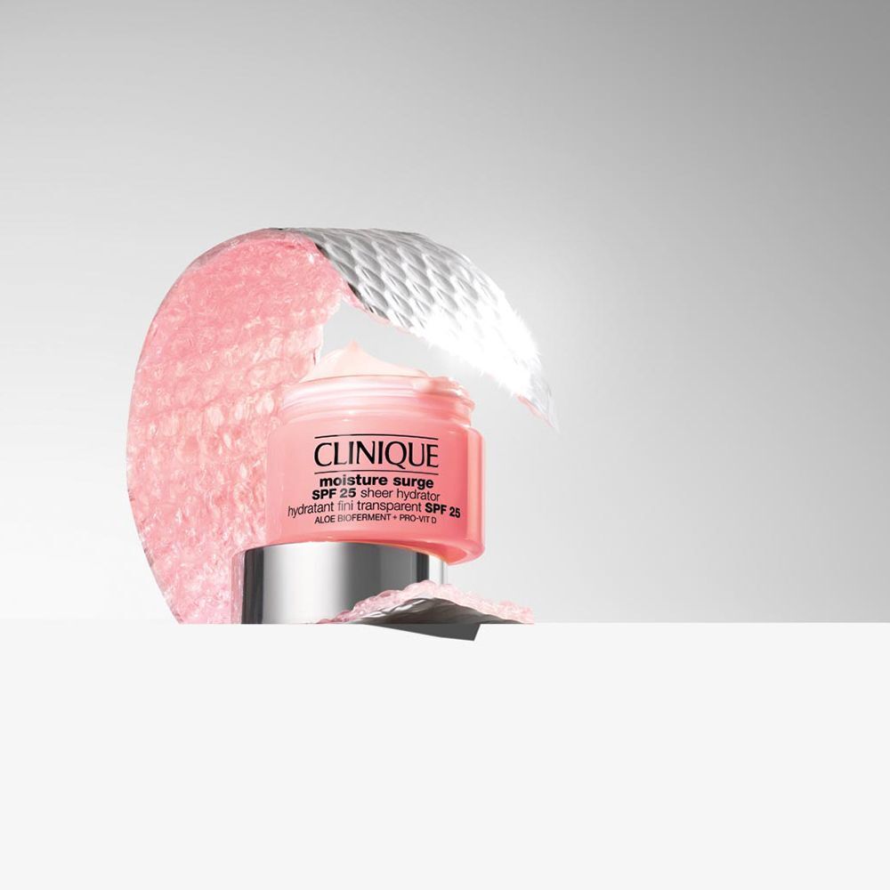 Un pot de Clinique Moisture Surge SPF 25 Sheer Hydrator entouré de matériau rose.