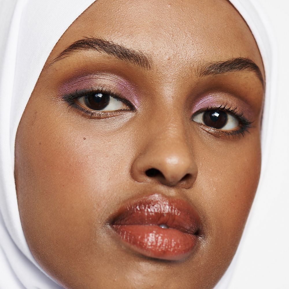 Portrait d'une femme avec des yeux et des lèvres maquillés, portant un hijab blanc.